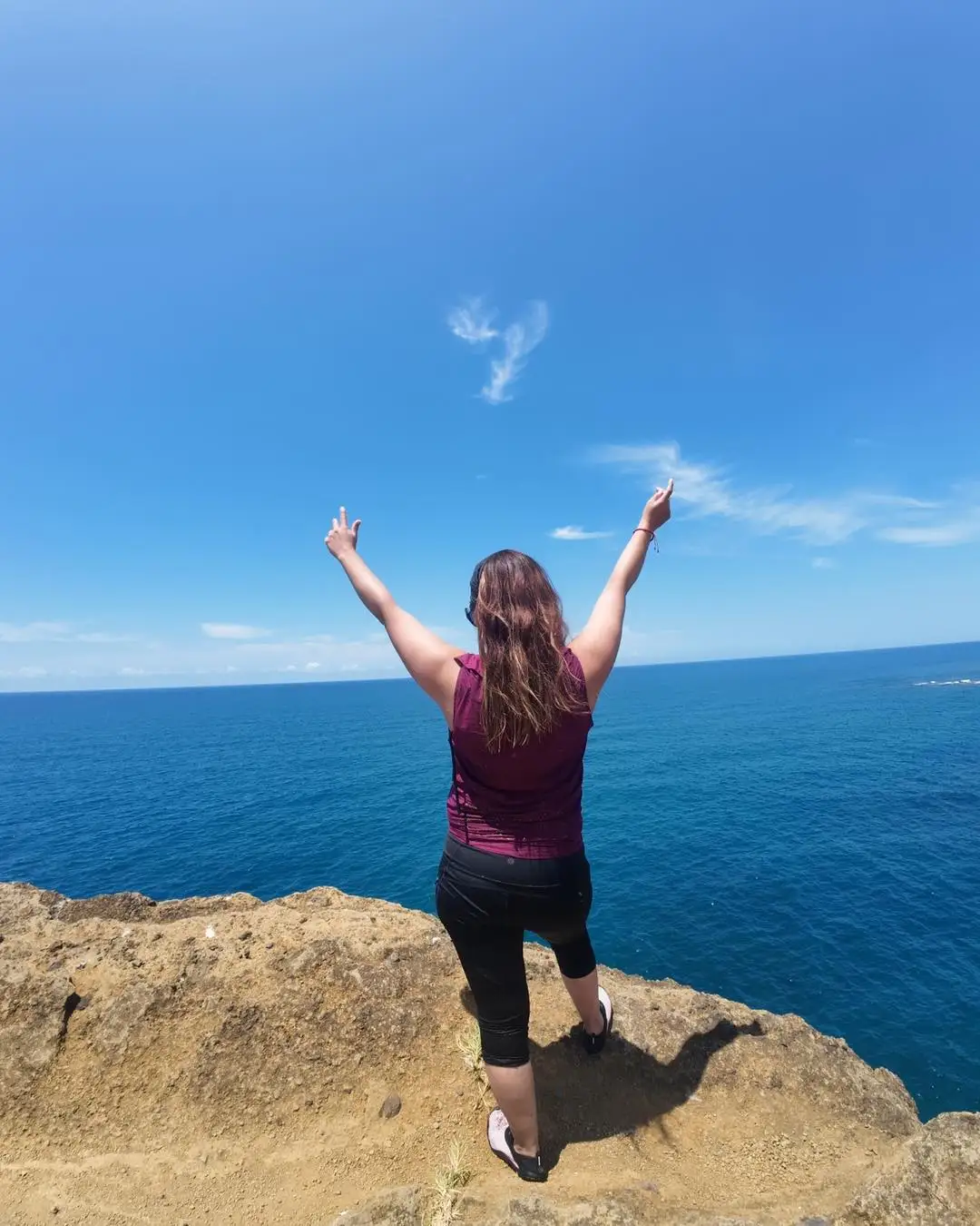Viajera con los brazos en alto frente al mar azul en un mirador de la costa de Los Tuxtlas