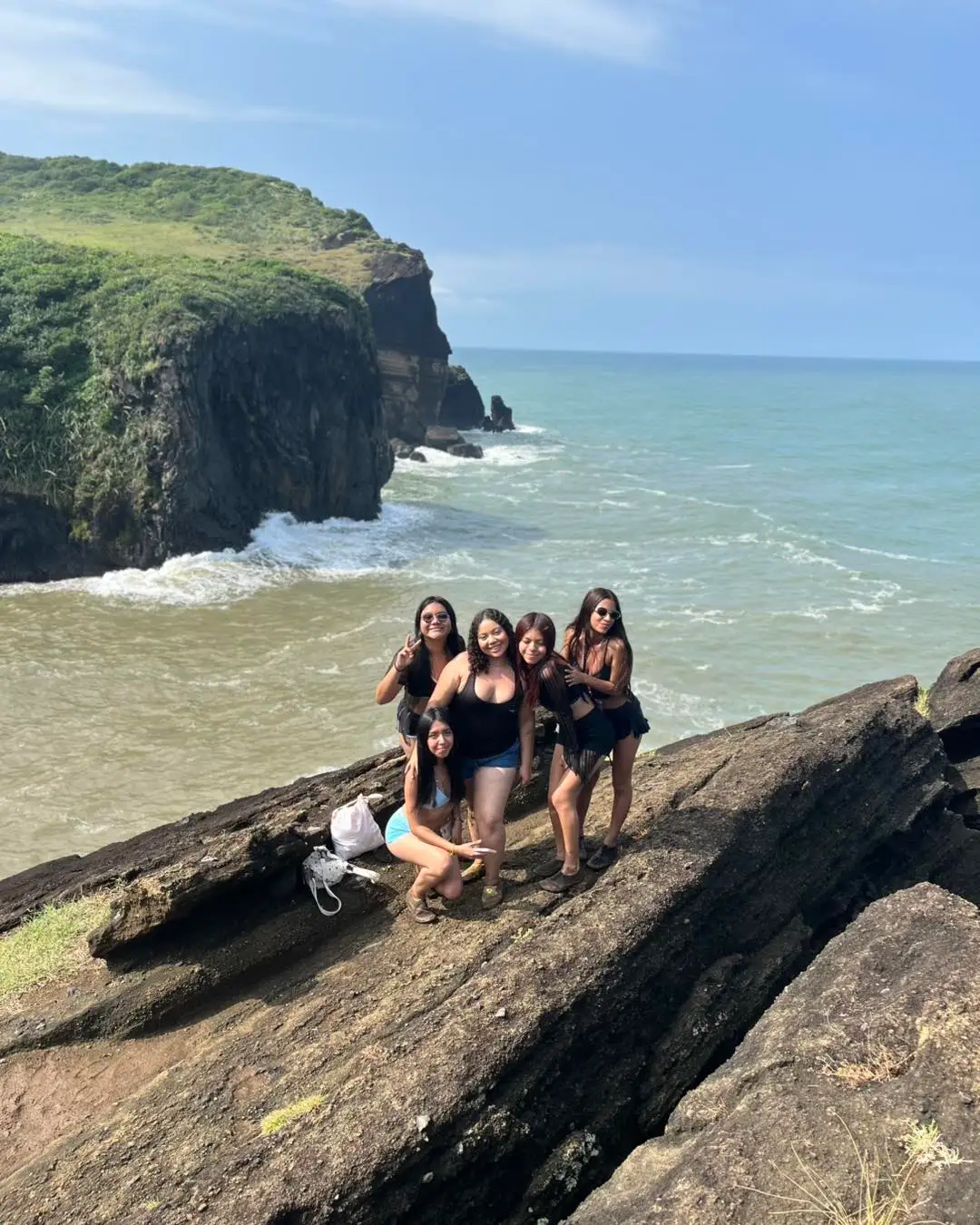 Grupo de amigas en las rocas con un acantilado y el mar de Los Tuxtlas de fondo