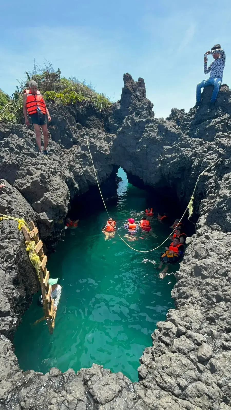 Visitantes nadando por el canal de roca volcánica que da acceso a la poza de Playa Ermita, en Los Tuxtlas, Veracruz