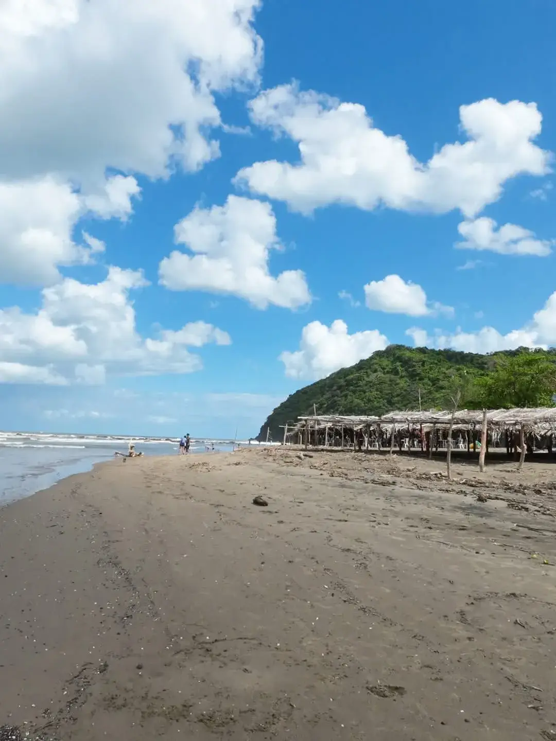 Playa de arena oscura de Montepío con enramadas de palma y el mar rompiendo, en la costa de Los Tuxtlas, Veracruz