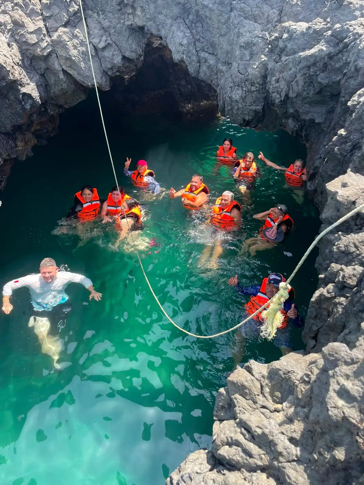 Guía de BoteTur ayudando a dos viajeras a bajar por las rocas hacia el mar