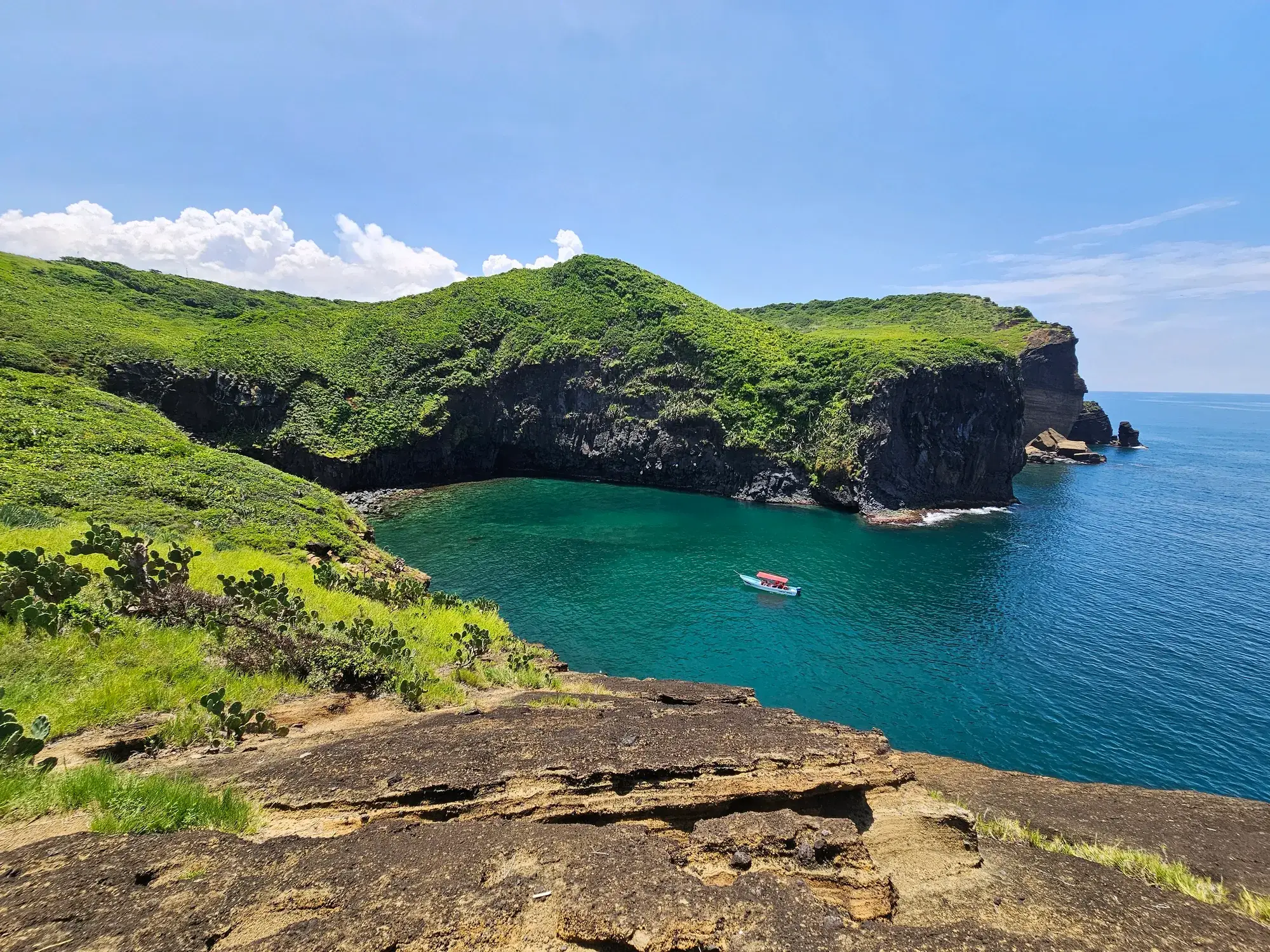 Ensenada de Roca Partida en Los Tuxtlas, Veracruz: acantilados verdes, agua turquesa y una lancha anclada en la bahía